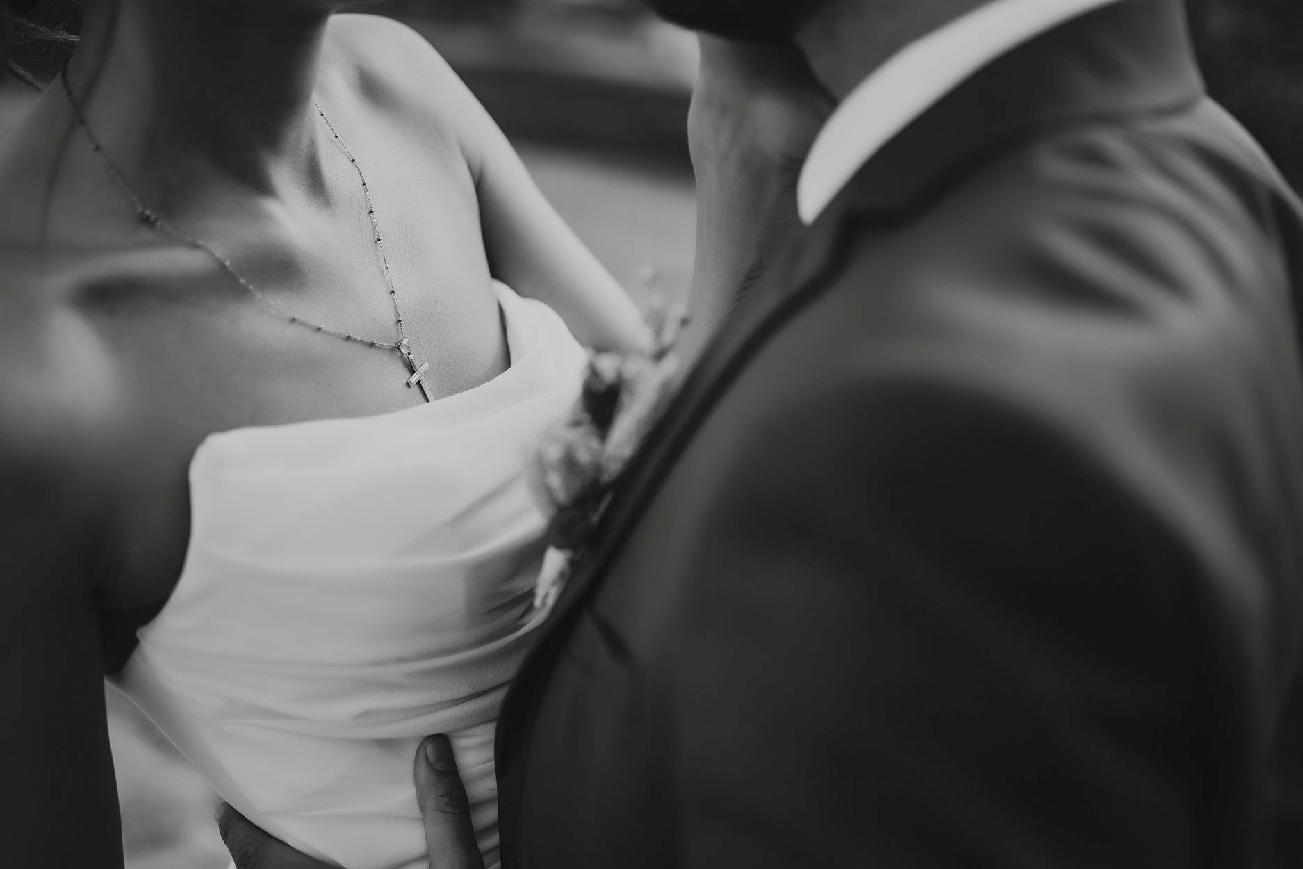 A close, soft frame of a hand resting at the small of a bride’s back while they dance