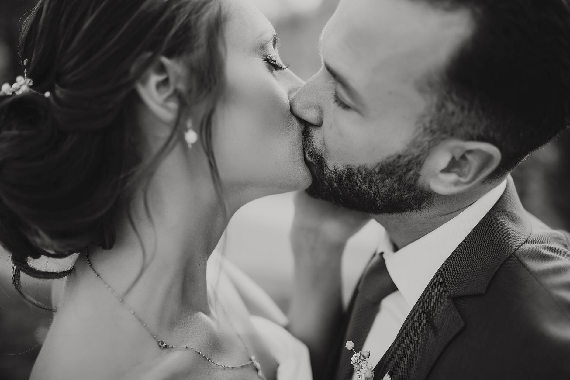 A very close frame of a couple kissing, her earring catching the light