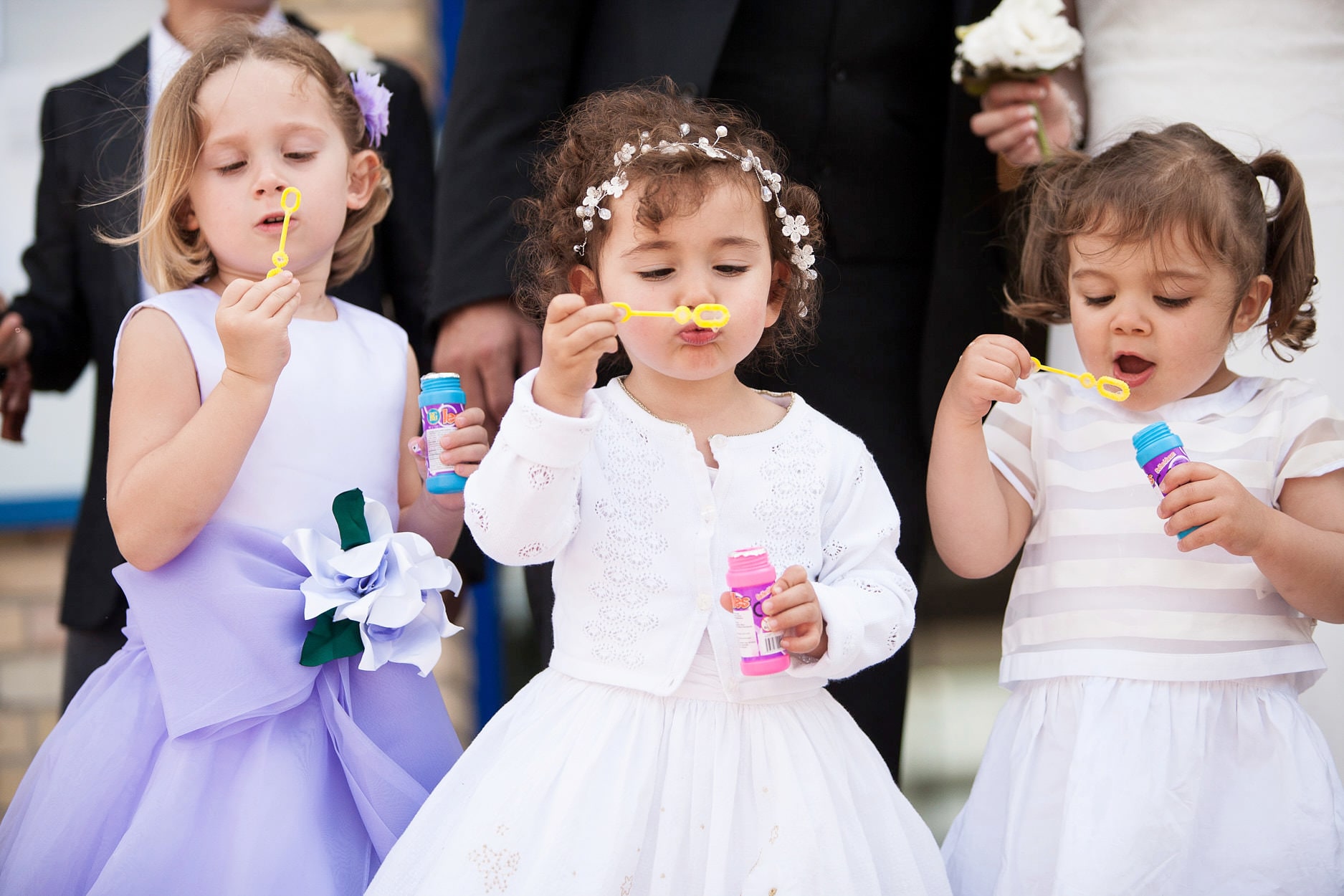 Three small flower girls blowing bubbles, entirely absorbed