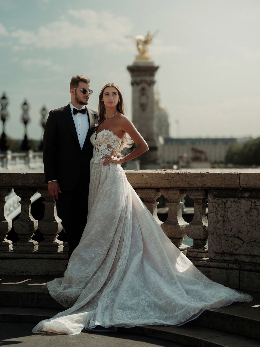 A couple standing at the foot of the gilded columns of the Pont Alexandre III
