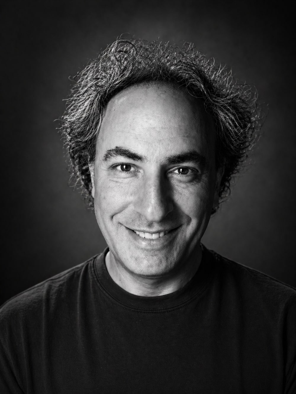 Ozgur Canbulat, photographed in black and white against a dark background