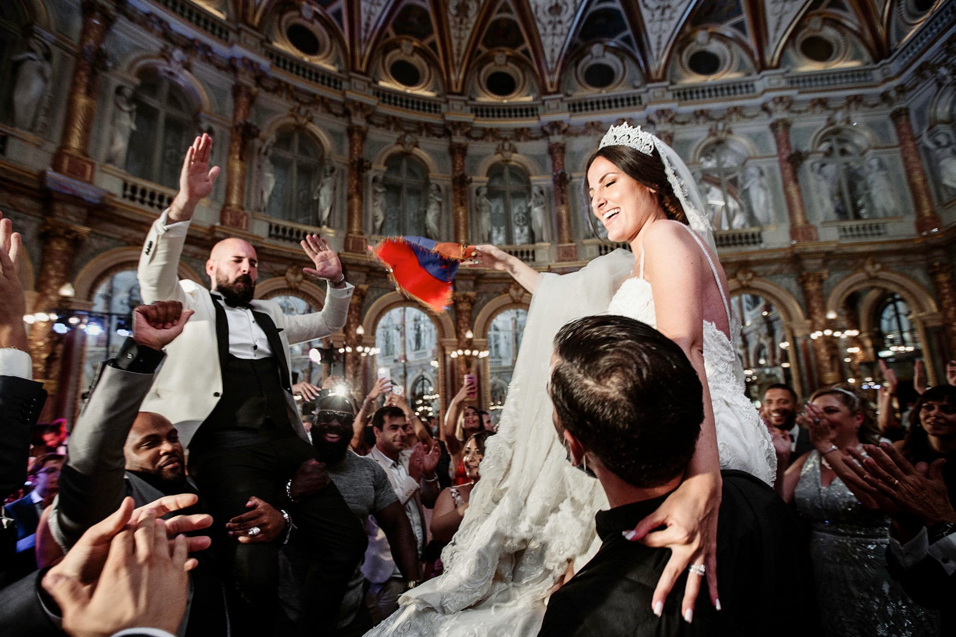 Petals thrown over a bride and groom as they come through a crowd in a painted ballroom