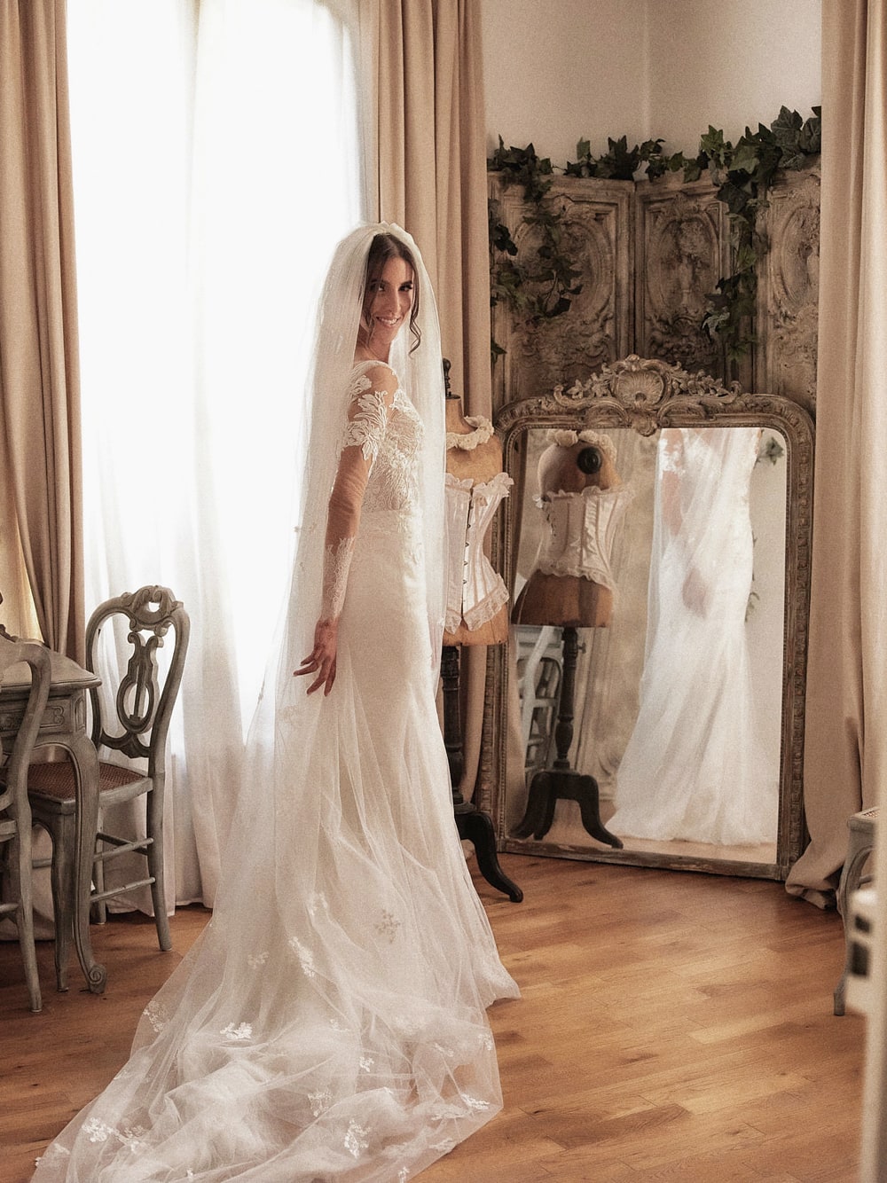 A bride alone in a panelled room, her train laid out across the floor behind her