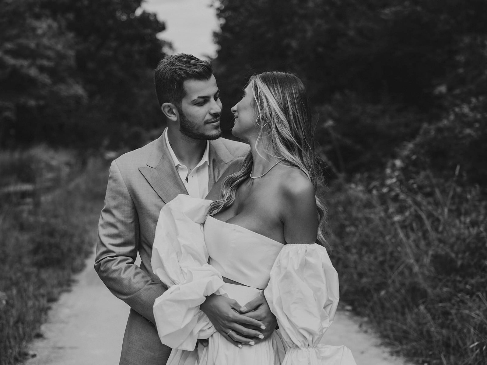 A couple holding each other on a park path, her puffed sleeves catching the light