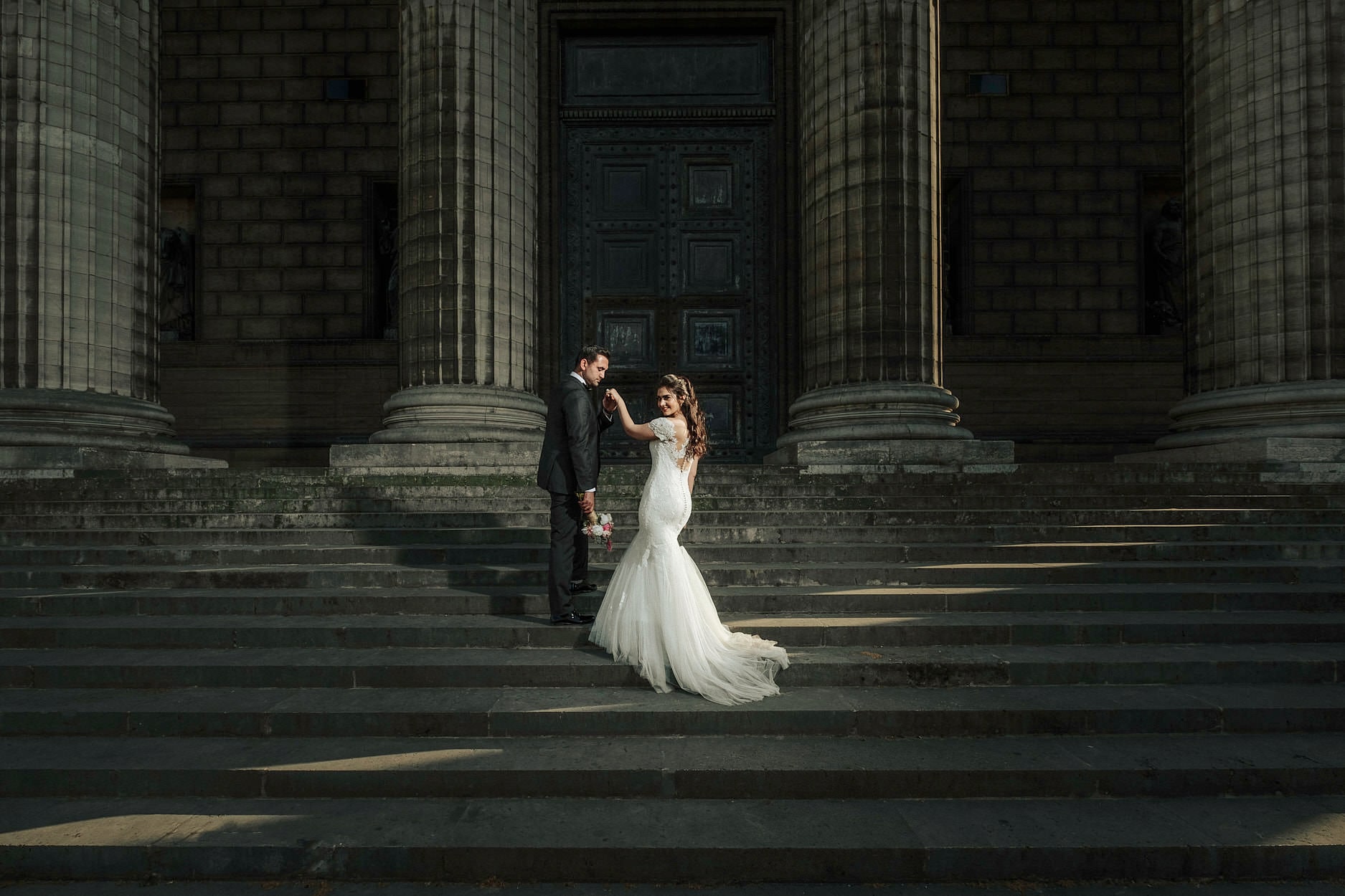 A couple dancing alone on the wide stone steps of a Paris church, dwarfed by the columns above them
