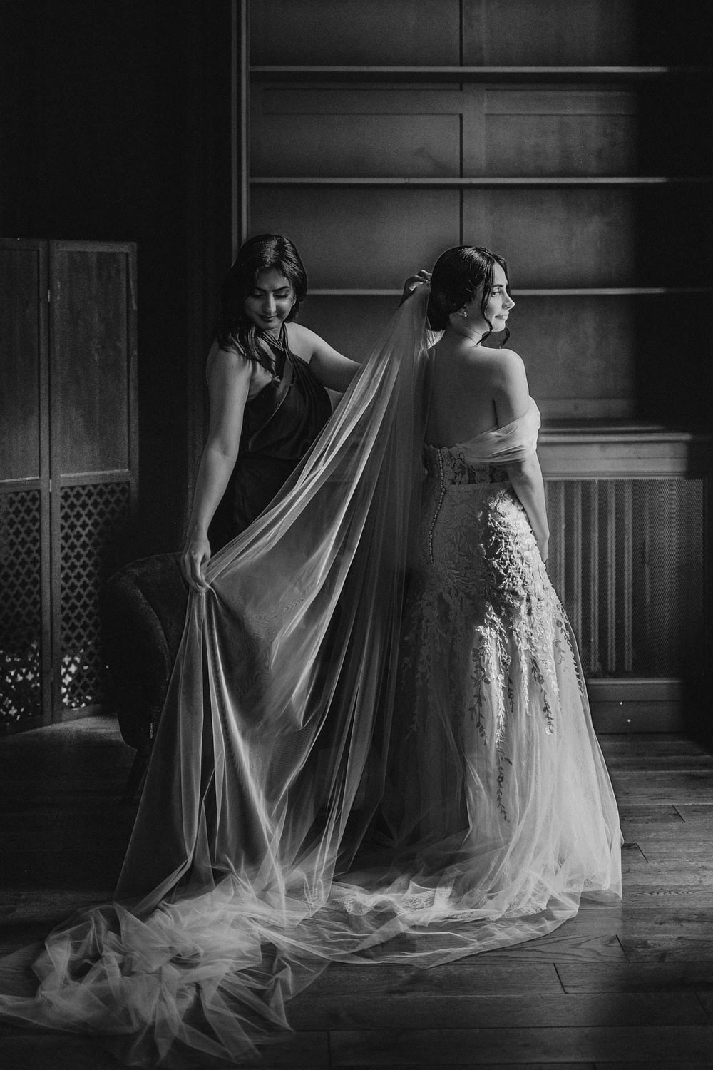 Two figures wrapped together beneath a long veil in a dark stairwell