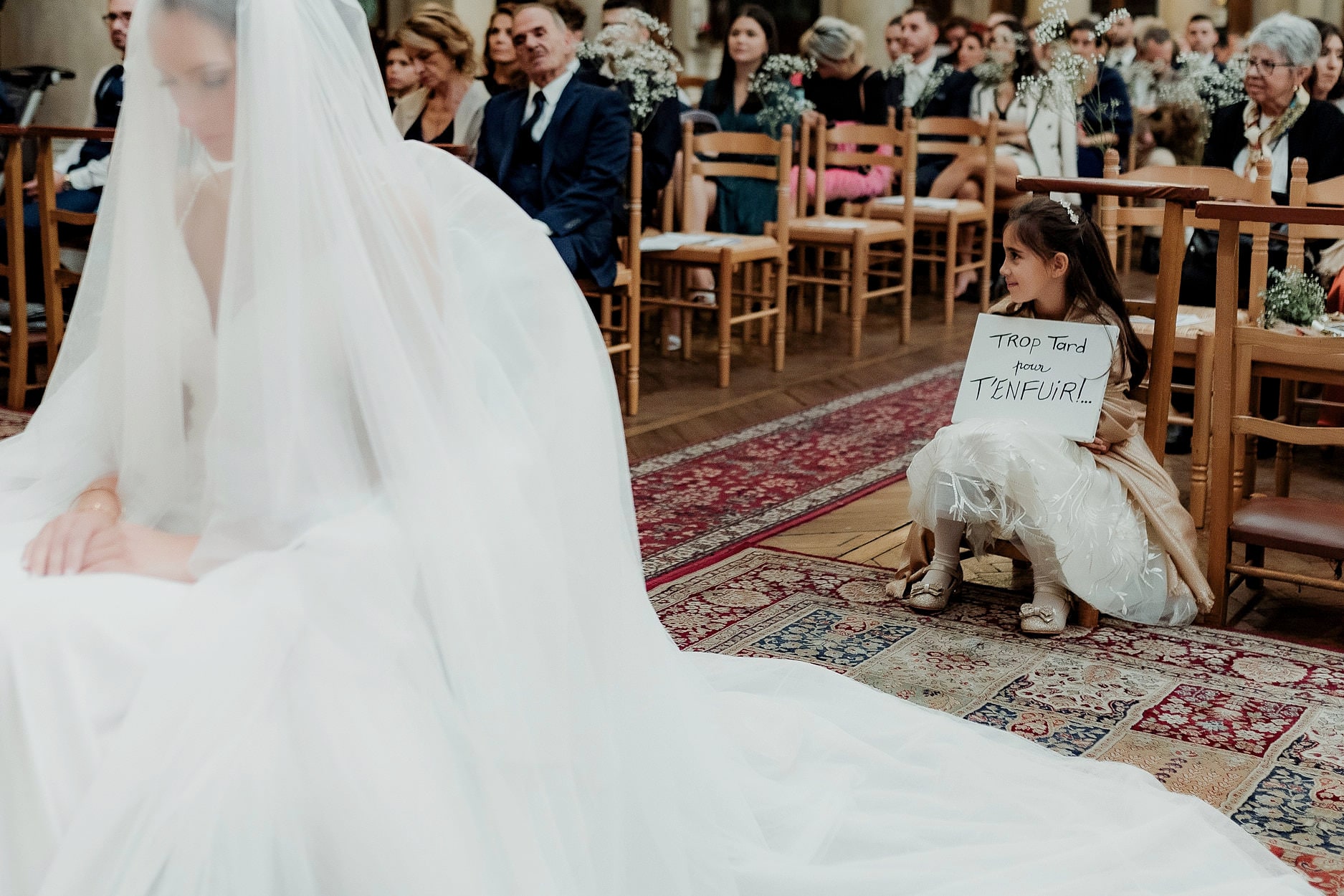 A bride at the head of the aisle, seated guests turning to watch her